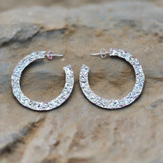 A pair of sterling silver hoop earrings with a textured surface.