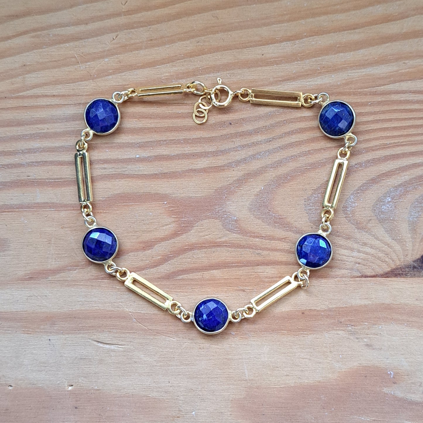 Gold plated sterling silver bracelet with lapis lazouli gemstones on a wooden surface