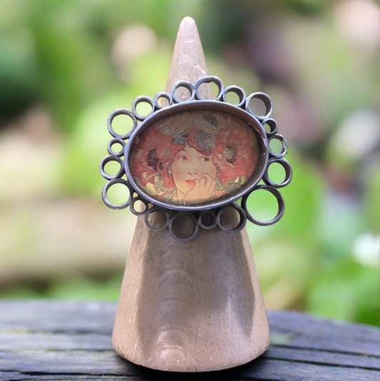 A handmade sterling silver ring with a vintage design, featuring a liquid resin coating that gives the appearance of solid glass.