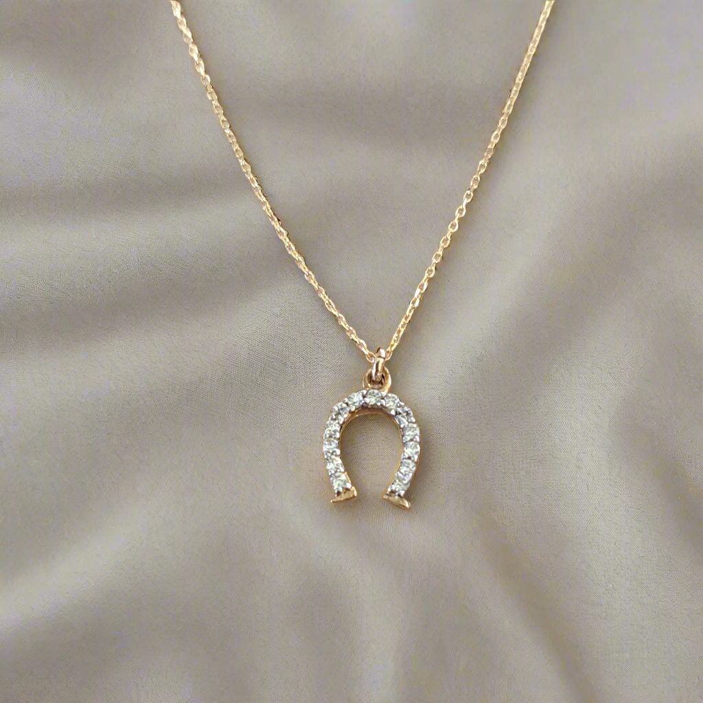 9K gold horse shoe necklace  with zirkons in a beige cloth