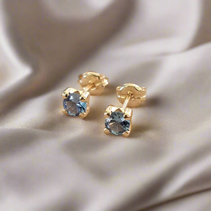  9Κ Gold earrings with blue zirkons on a luxury cloth
