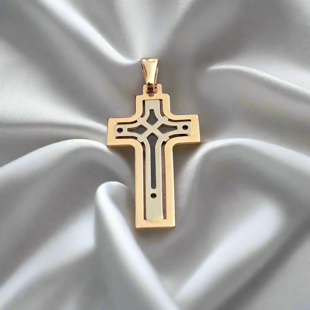 A 14k white and gold cross pendant displayed on a silky surface.