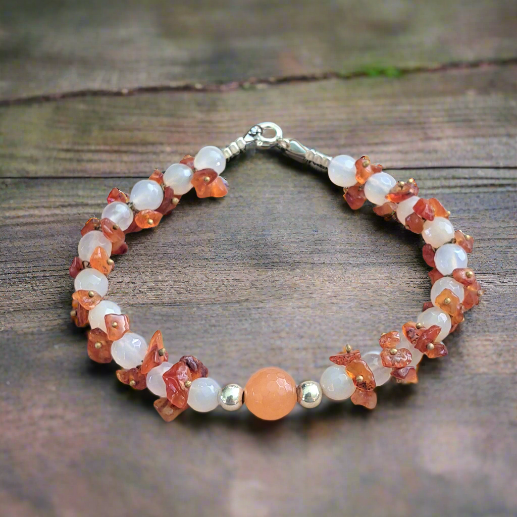 Handmade bracelet with orange and white agates and sterling silver elementsand on a wooden surface