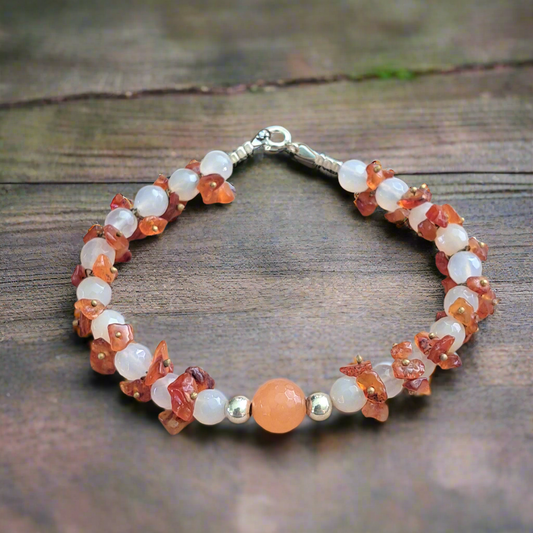 Handmade bracelet with orange and white agates and sterling silver elementsand on a wooden surface