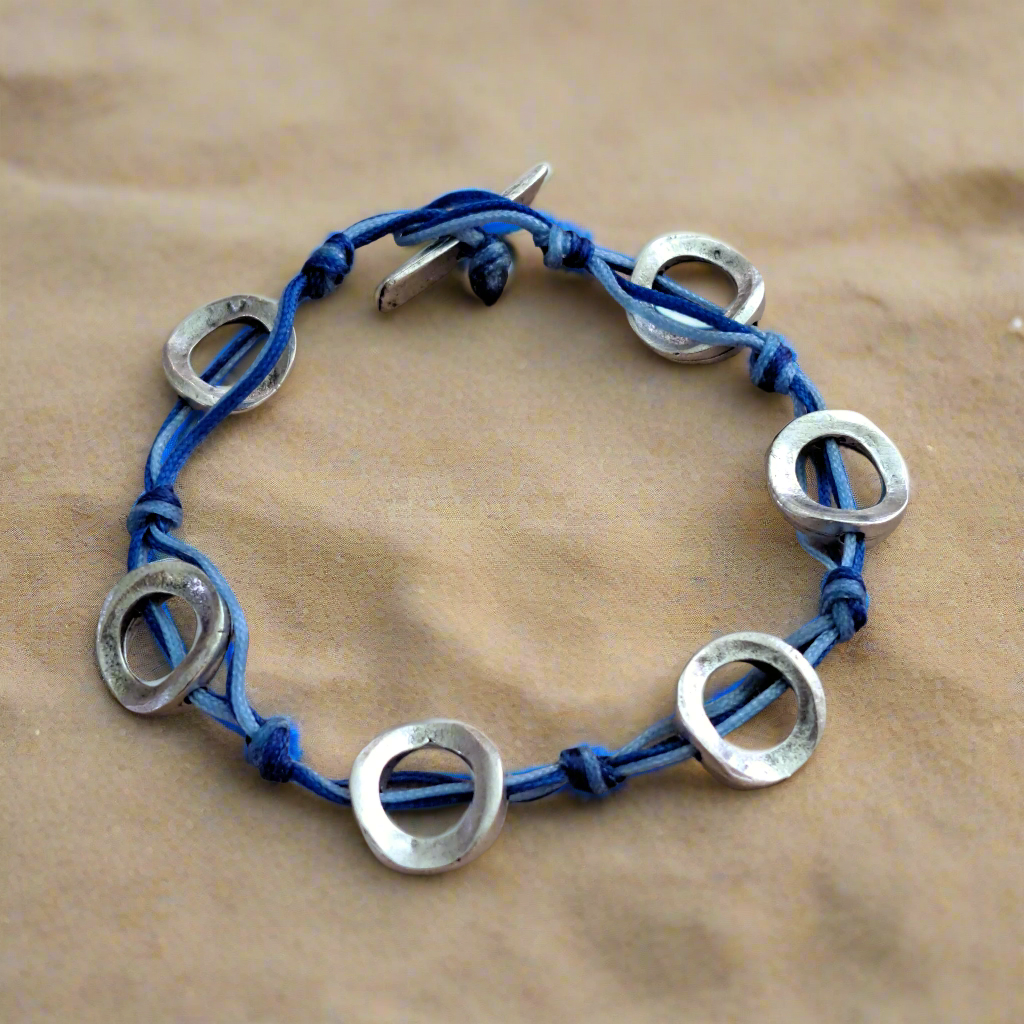 Bracelet with blue cord and silver circular metal pieces.