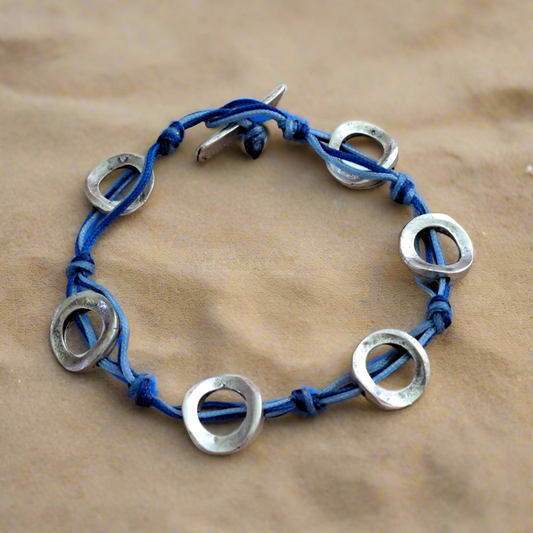 Bracelet with blue cord and silver circular metal pieces.