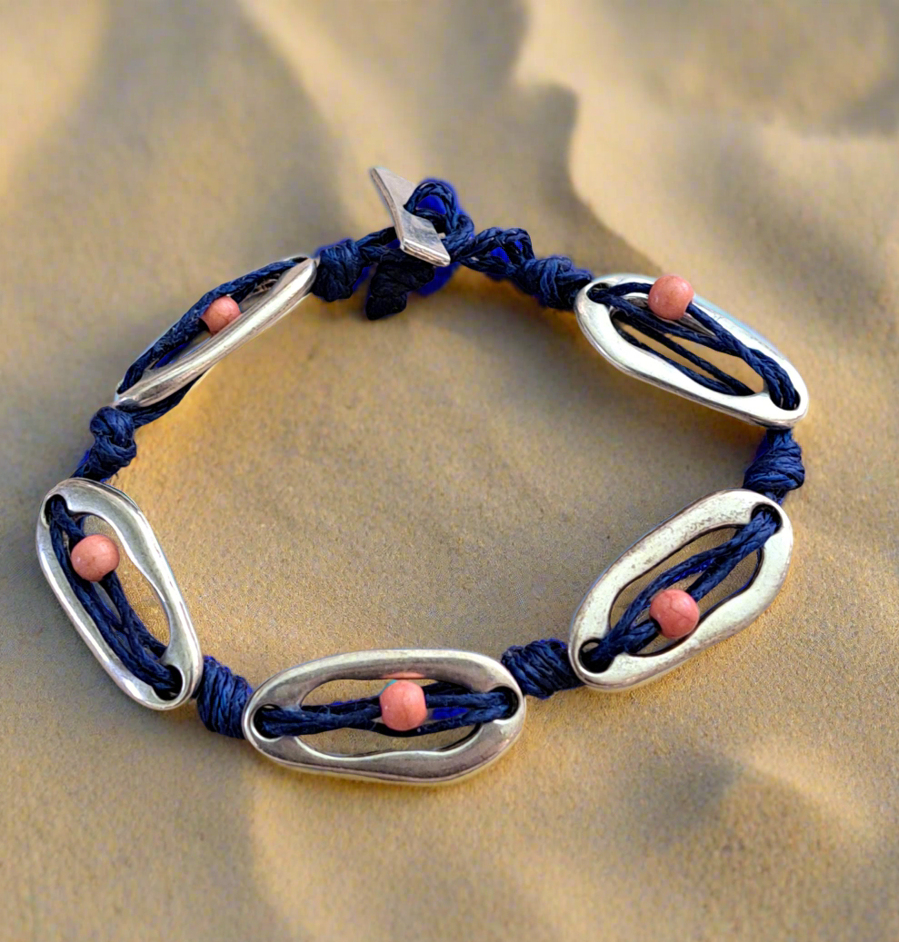 Bracelet with german silver oval-shaped elements and pink beads on a sand background