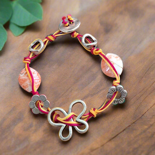 Bracelet with pink and yellow cord and  floral-shaped clasps.