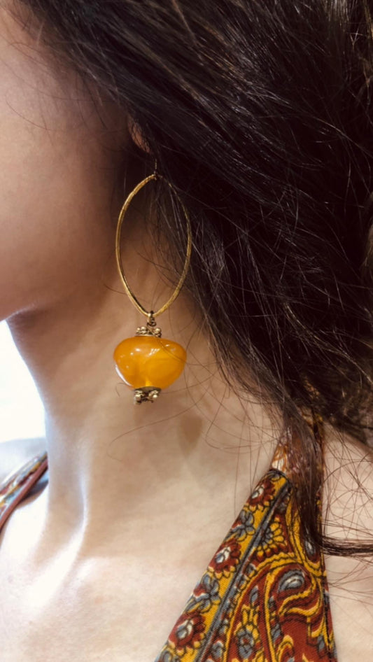 Close-up of a person wearing a  sterling silver oval earring with a yellow  amber.