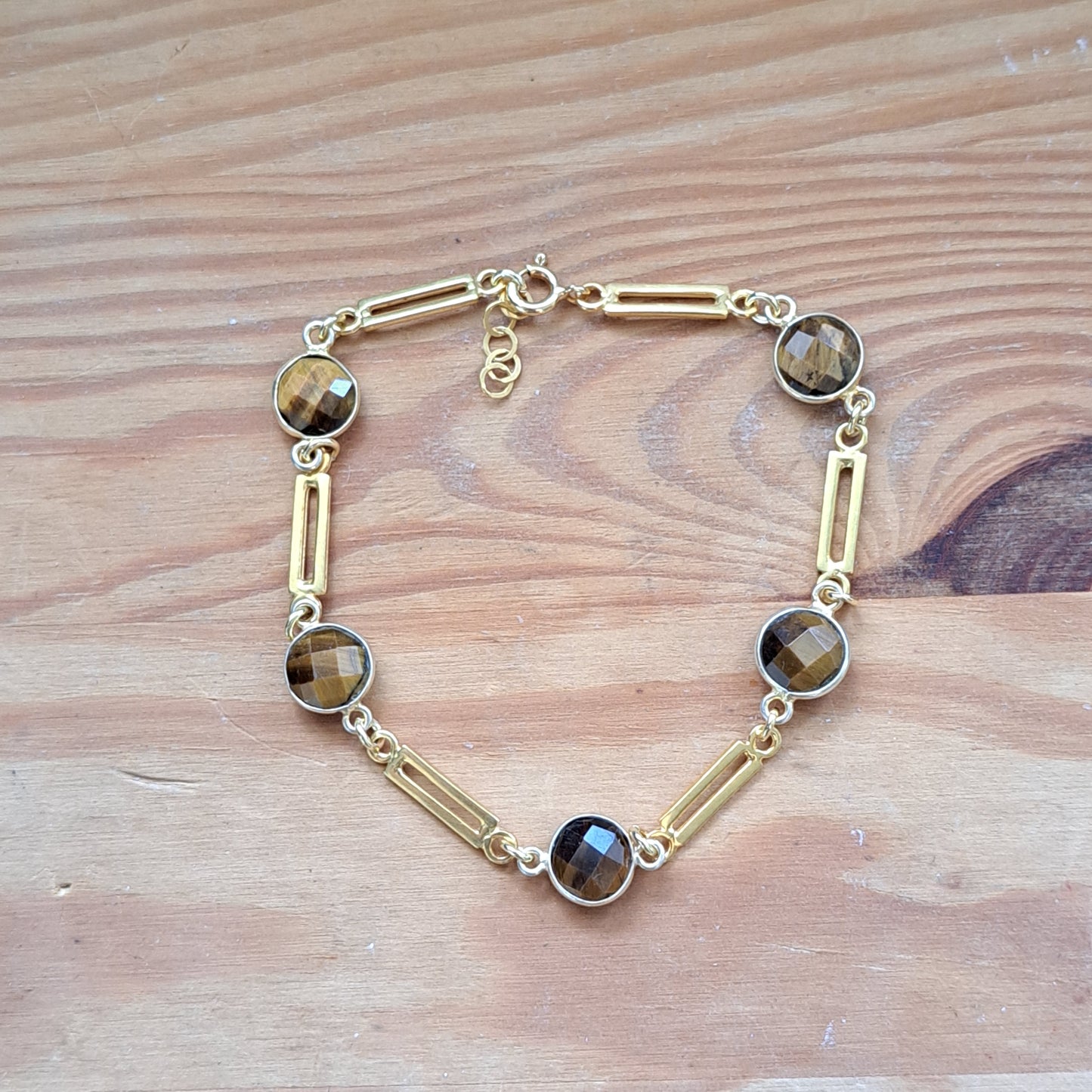 Gold plated sterling silver bracelet with tiger eye  gemstones on a wooden surface