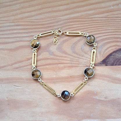 Gold plated sterling silver bracelet with tiger eye  gemstones on a wooden surface