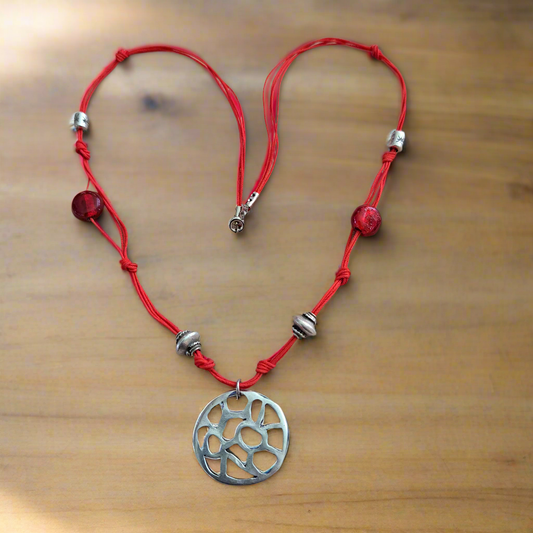 Red string necklace with metallic beads and red glass beads with a round central element pendant .