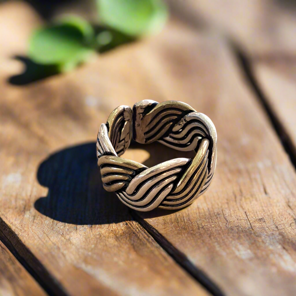 Silver and bronze  ring with wavy design on a wooden surface