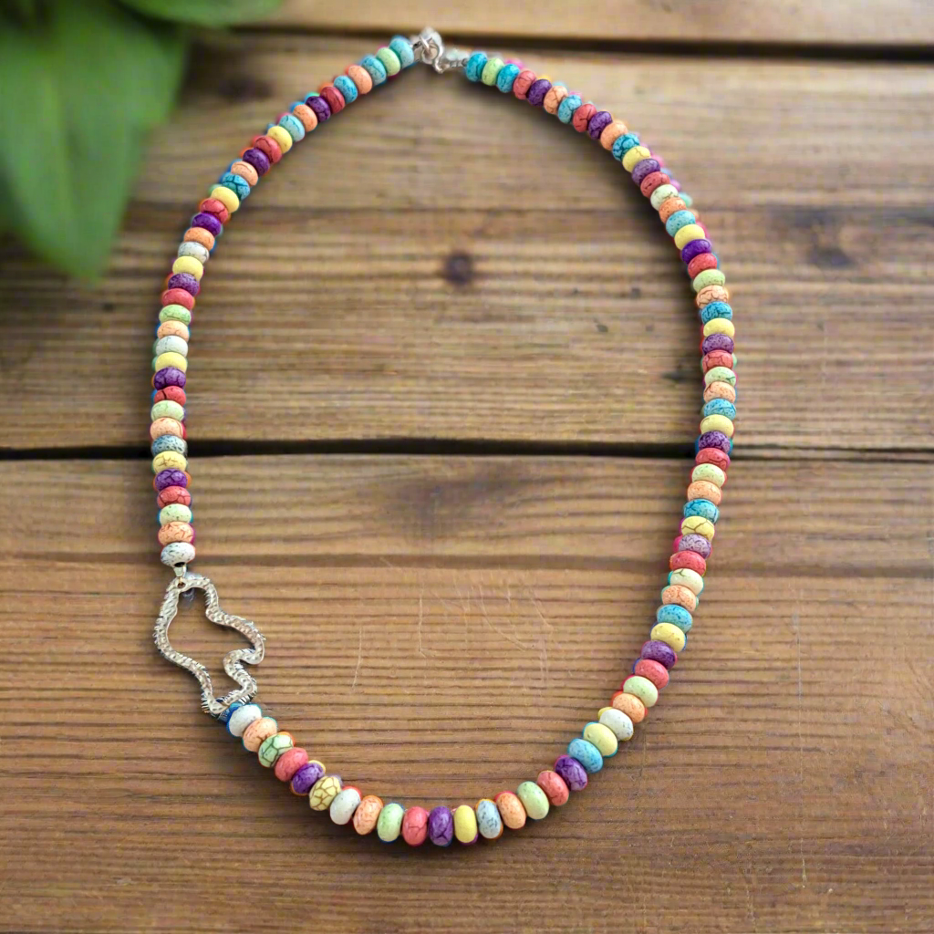 Colorful beaded necklace with a silver bird pendant on a wooden surface
