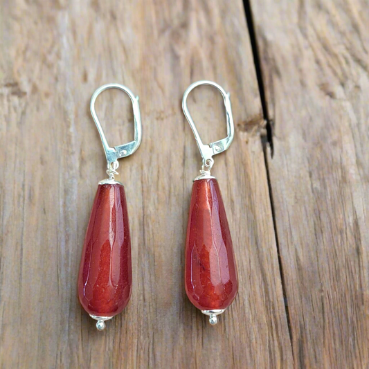 Pair silver earrings with of red teardrop  cornelians  on a wooden surface