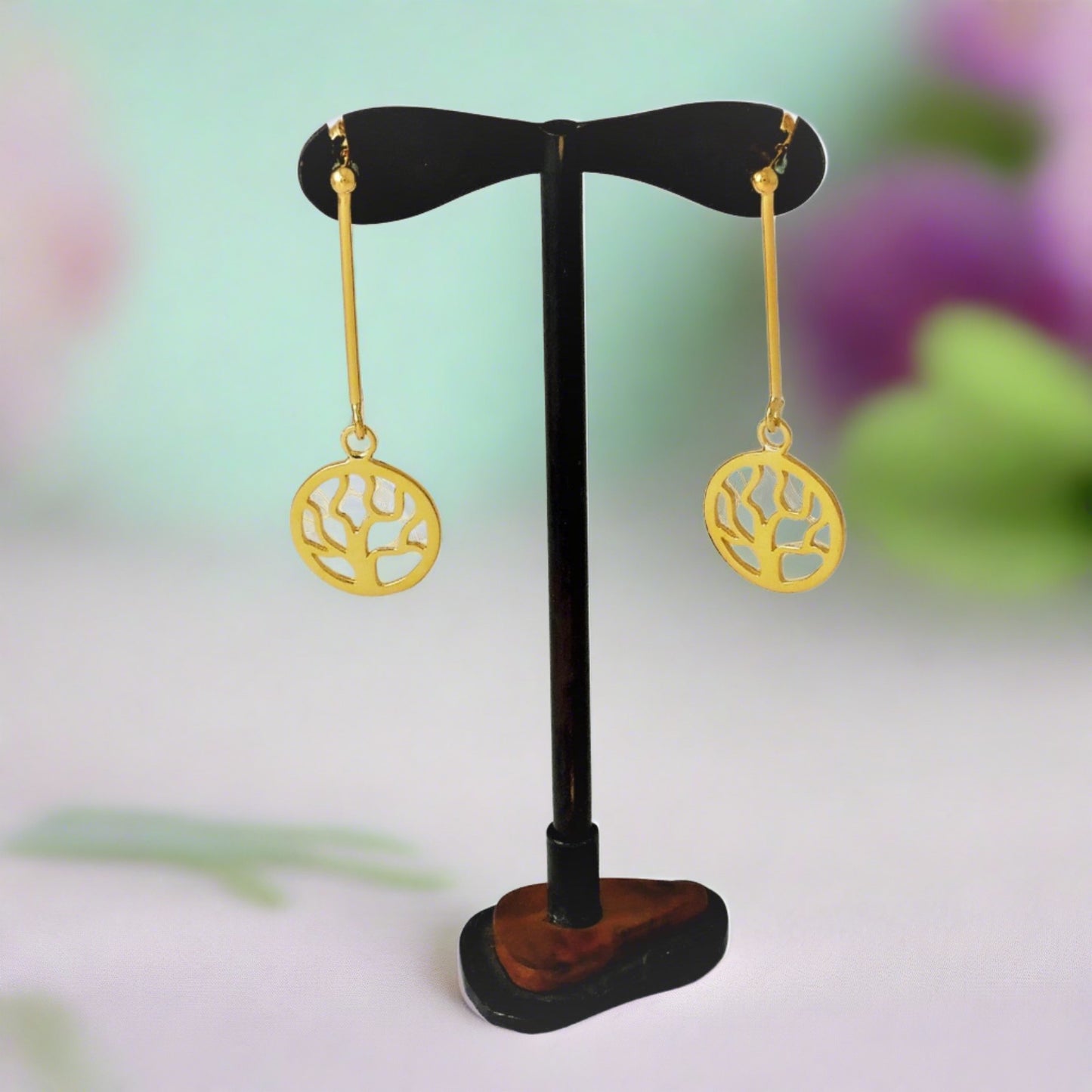 “Earrings made of silver, gold-plated, with  a thick  vertical wire, and beneath the wire hangs a round design with a tree without flowers and leaves.The design is perforated and elegant.”
