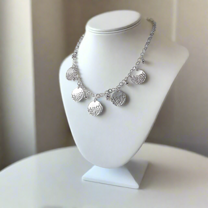 Silver necklace on a white mannequin bust against a neutral background