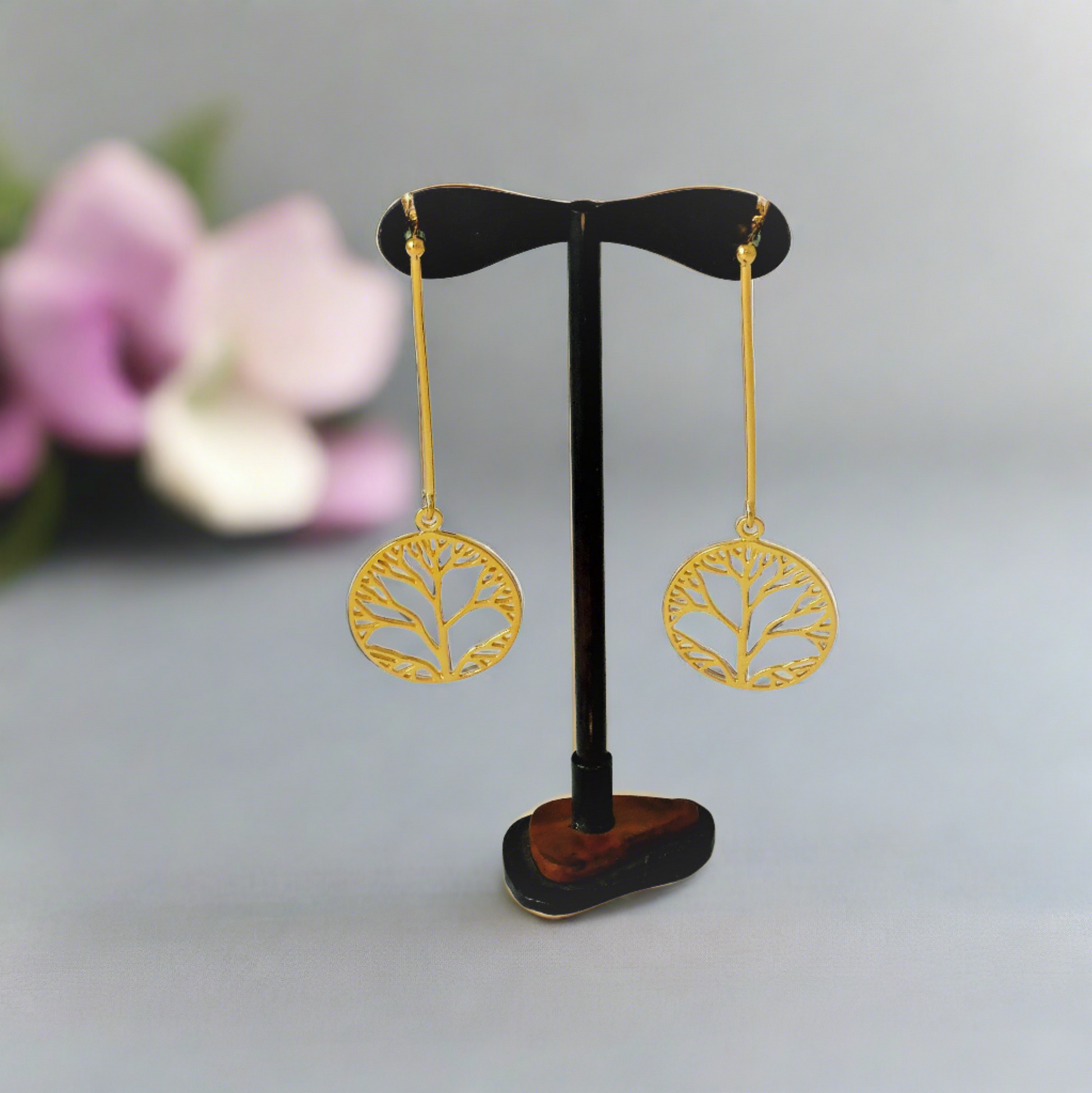 Tree of life long earrings in a stand . Earrings made of silver, gold-plated, long with thick wire, and beneath the wire hangs a round design with the tree . The design is very elegant.”