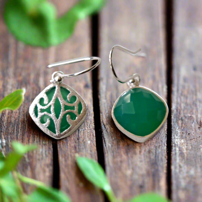 Green agate  earrings with silver designs on a wooden surface