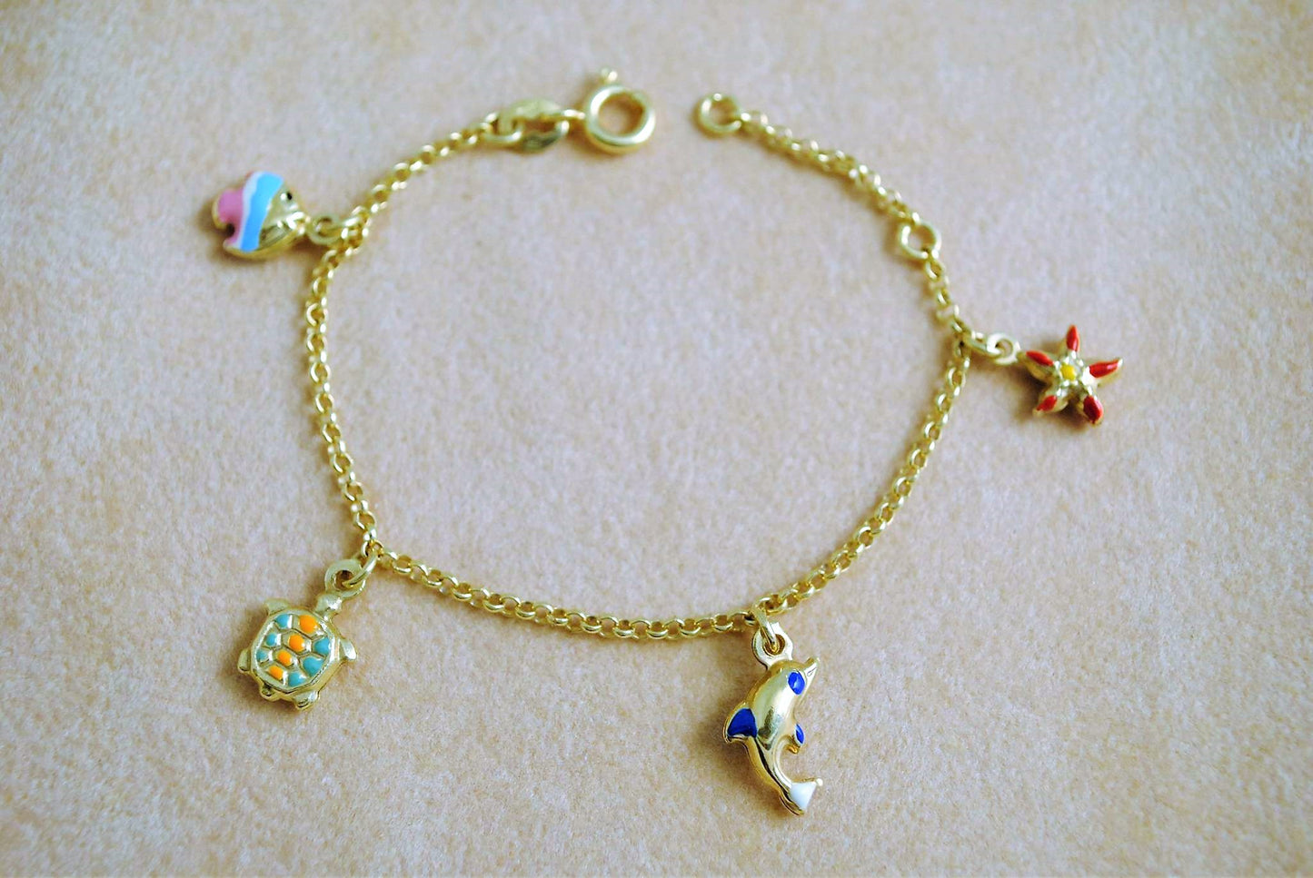 Gold baby bracelet with dolphin, fish, star fish and a turtle