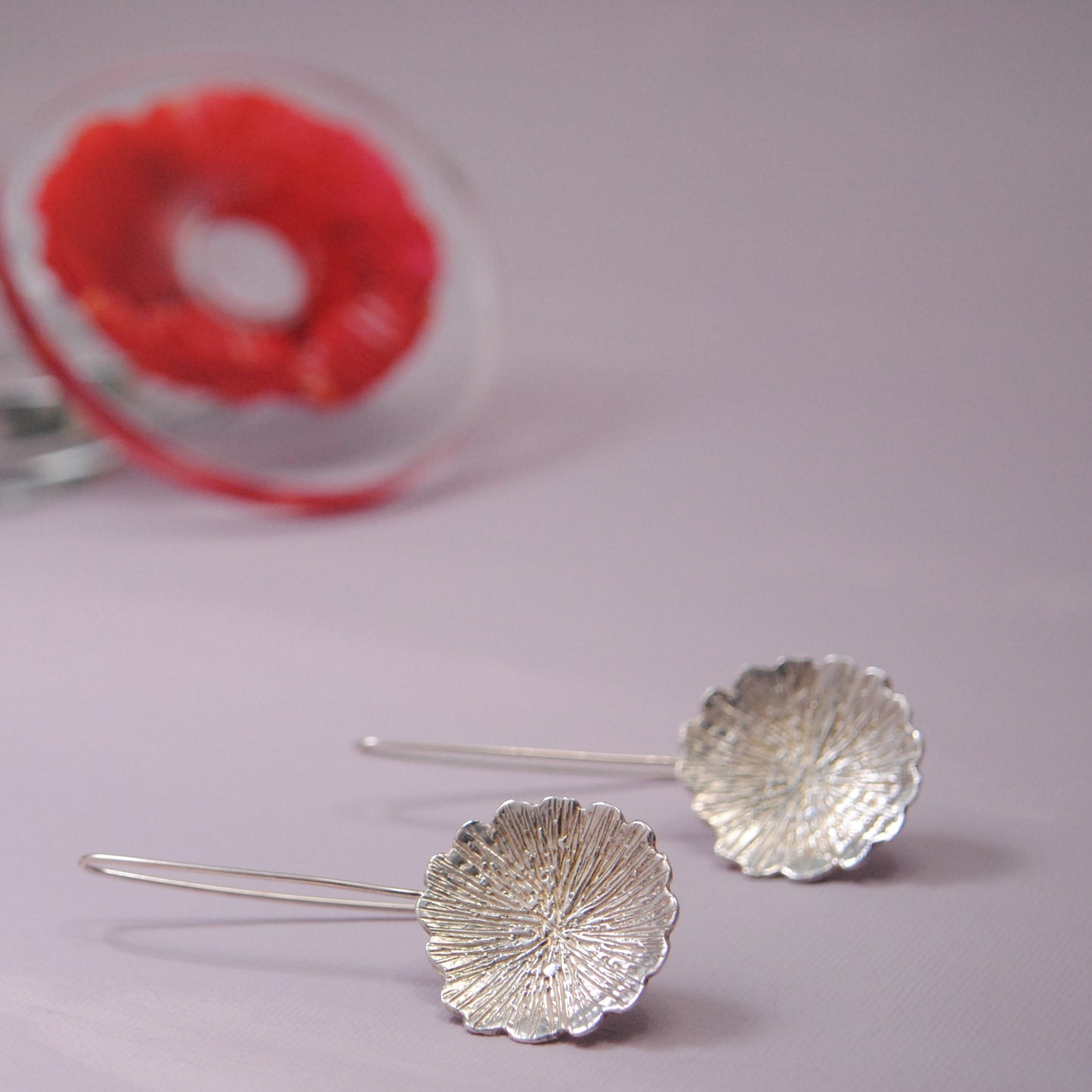 Long sterling silver earrings with a design of a flower . Flowers hang from a long silver wire.